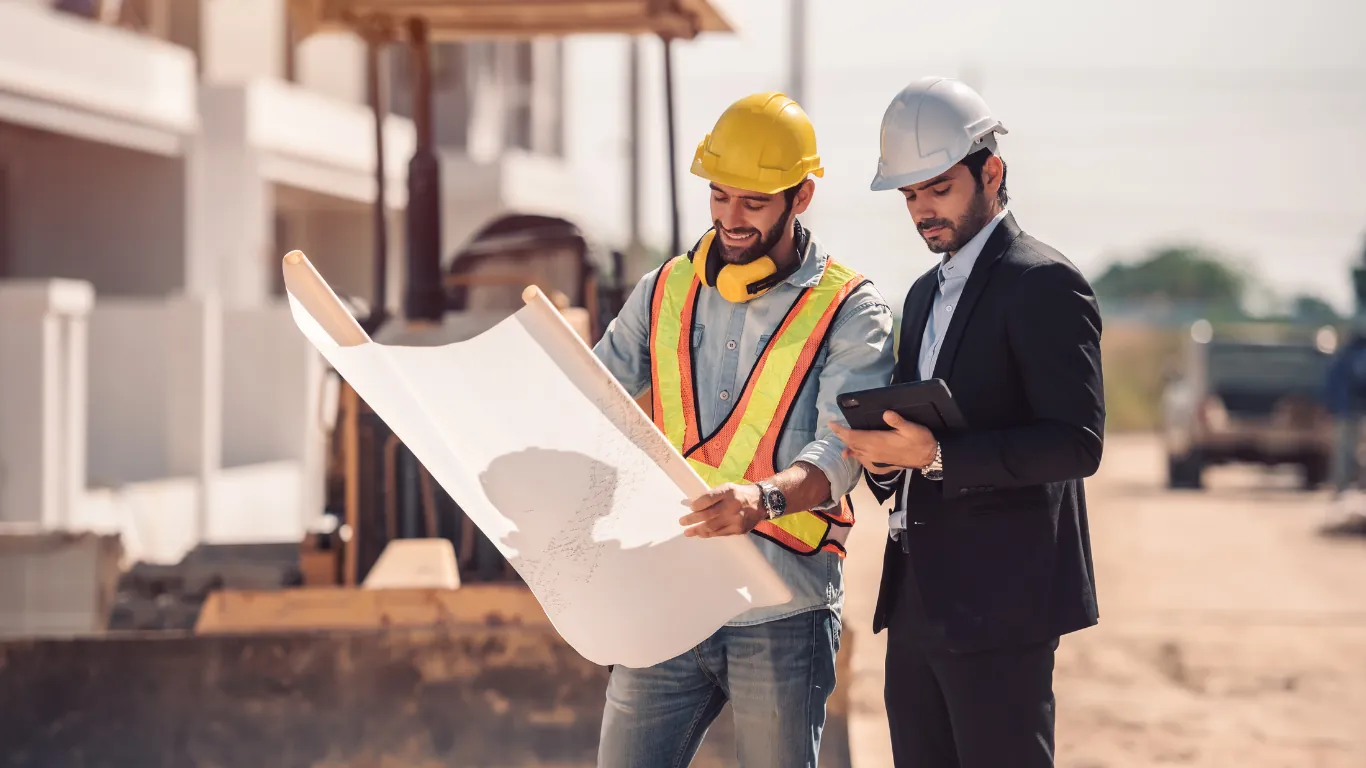 Works manager and director reviewing construction blueprints